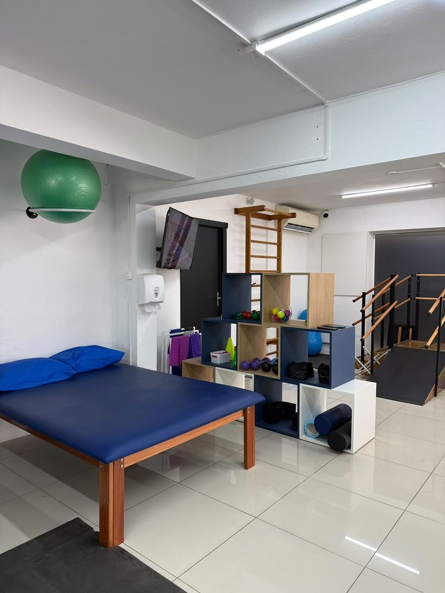 Sala de reabilitação com maca, espaldar e barras paralelas
